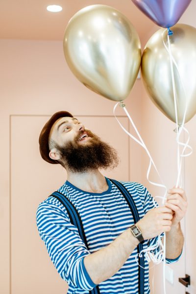 Festive man with balloons indoors