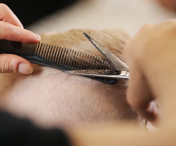 Men's hairstyling, haircutting, in a barber shop or hair salon.
